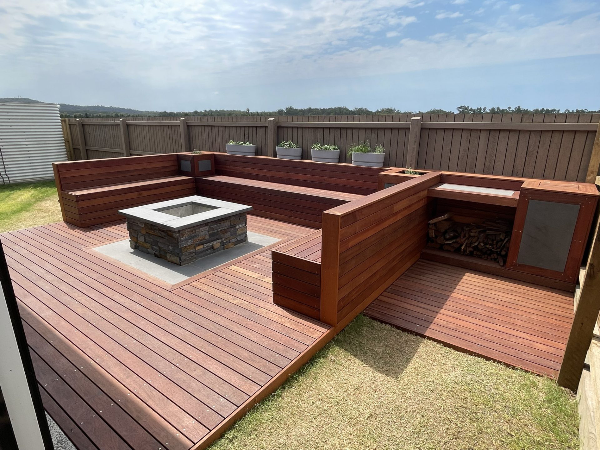 Completed hardwood deck with bench seating, planters and fire pit